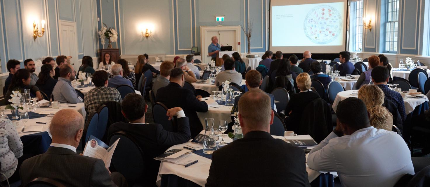 Landscape photo of symposium attendees listening to speaker