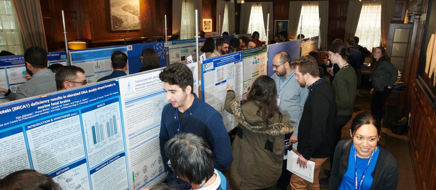 Candid photo of symposium attendees exploring graduate student poster presentations