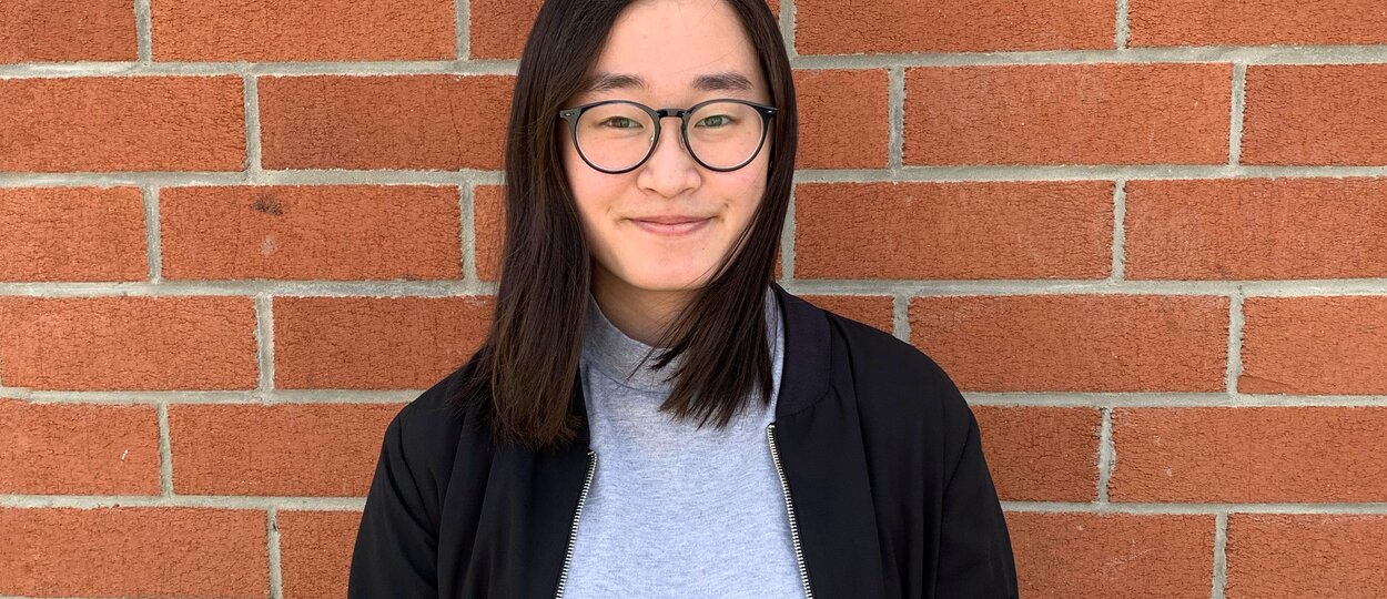 Portrait photo of U of T student Jenny Cheung against brick wall
