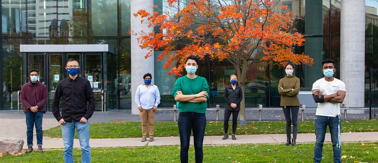 U of T Pharmacy and Engineering Researchers in front of Pharmacy building, physically distanced and wearing masks