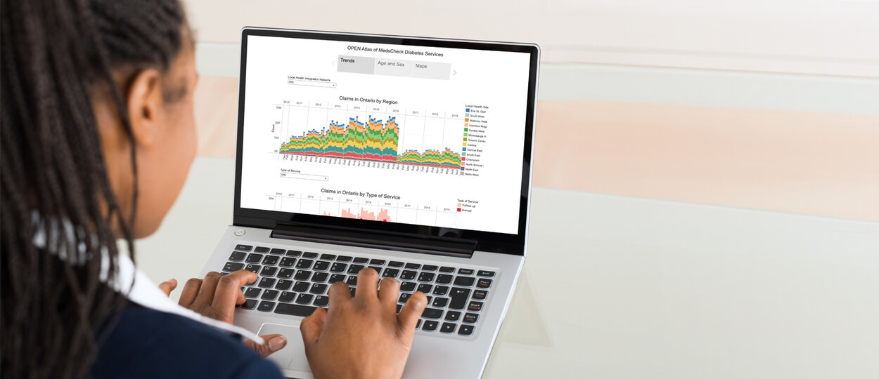 Photo of woman sitting at computer, reviewing OPEN Medication Atlas