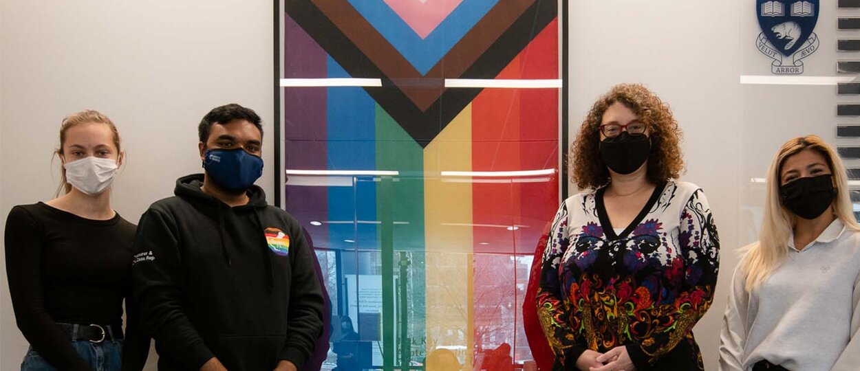 Members of PharmaPride student group alongside Dean Lisa Dolovich in front of inclusion pride flag