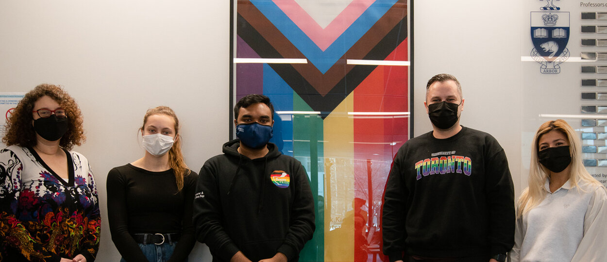 Members of PharmaPride student group alongside Dean Lisa Dolovich and Jaris Swidrovich in front of inclusion pride flag