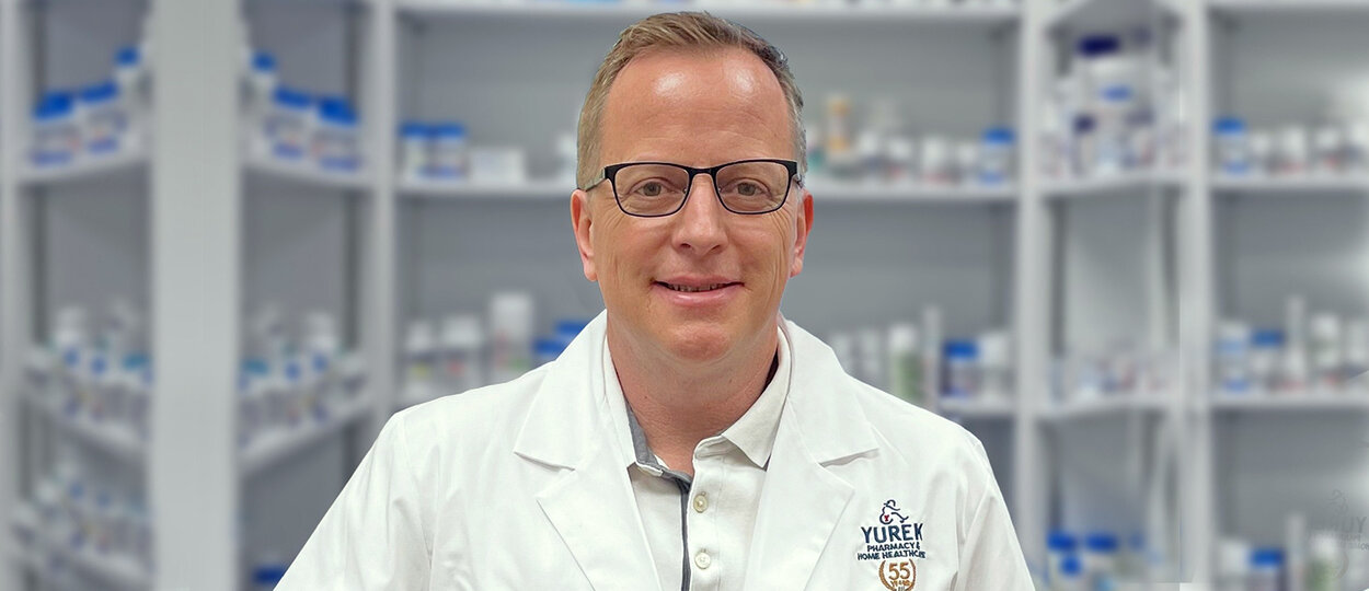 Portrait of Pharmacist Jeff Yurek in front of medication shelves