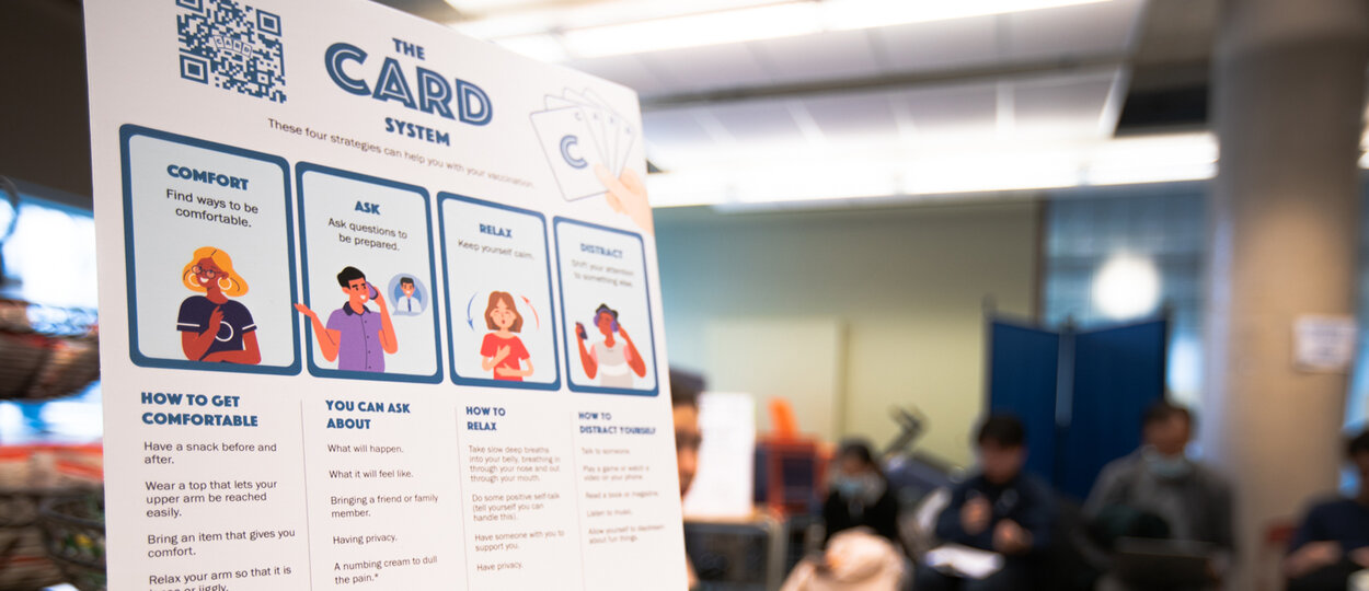 Image of CARD information poster with blurred patients sitting in waiting area behind