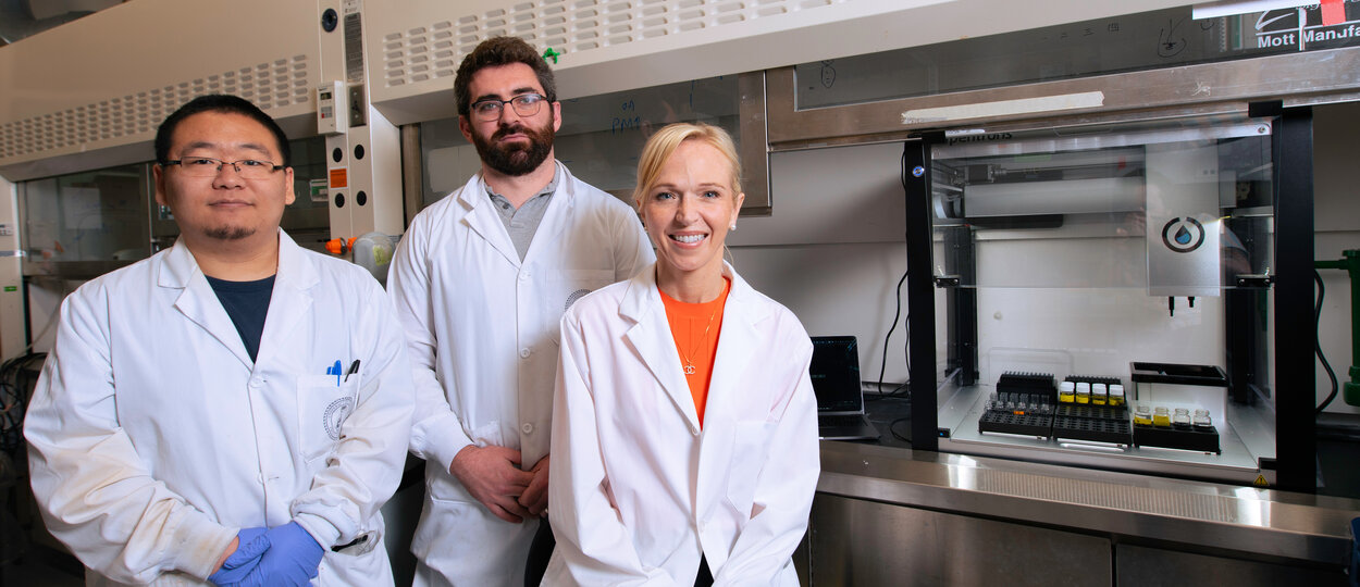 Phd Trainee Zeqing Bao, Allen Lab Director Pauric Bannigan and Professor Christine Allen posing in the Allen lab next to self-driving lab prototype