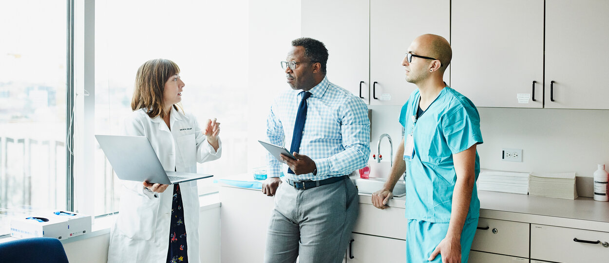 Female doctor leading medical team discussion in hospital exam room