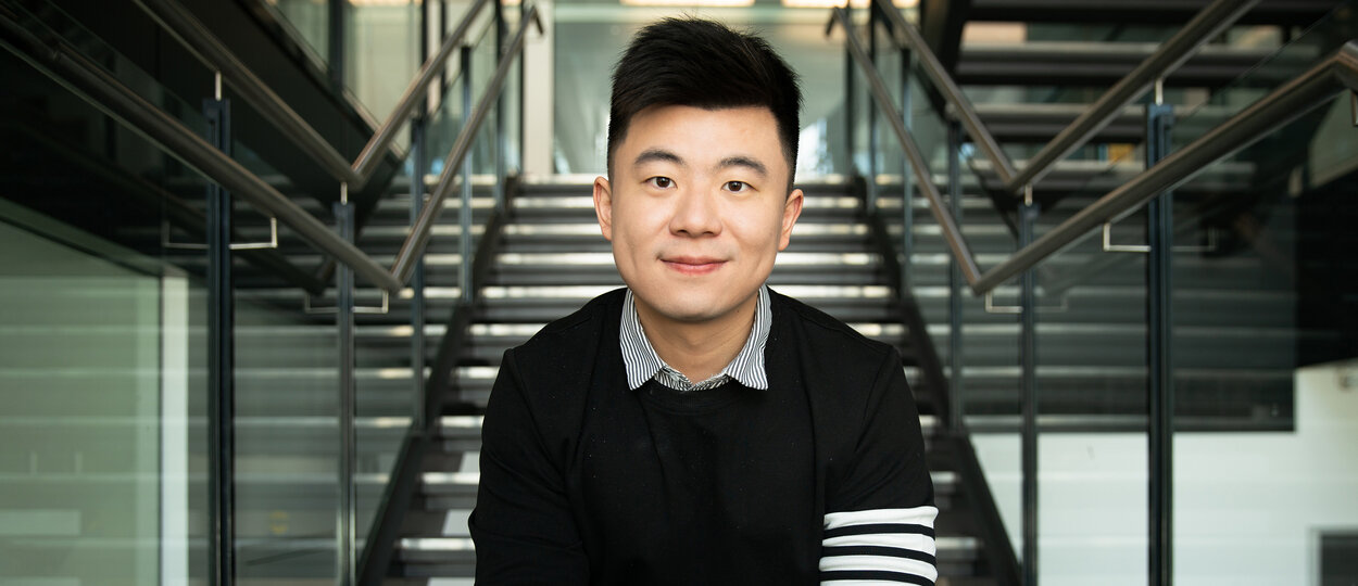 Professor Bowen Li sitting on steps at the Leslie Dan Faculty of Pharmacy