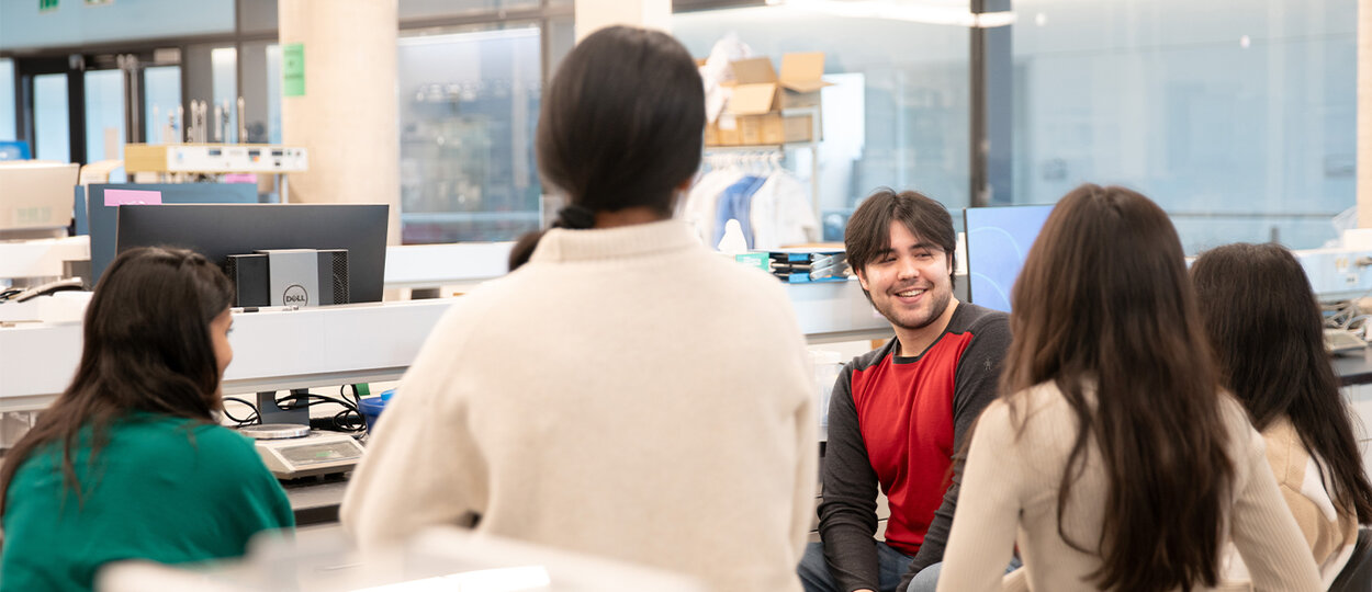 Lab technician Quinn Matthews surrounded by students during protein purification activity