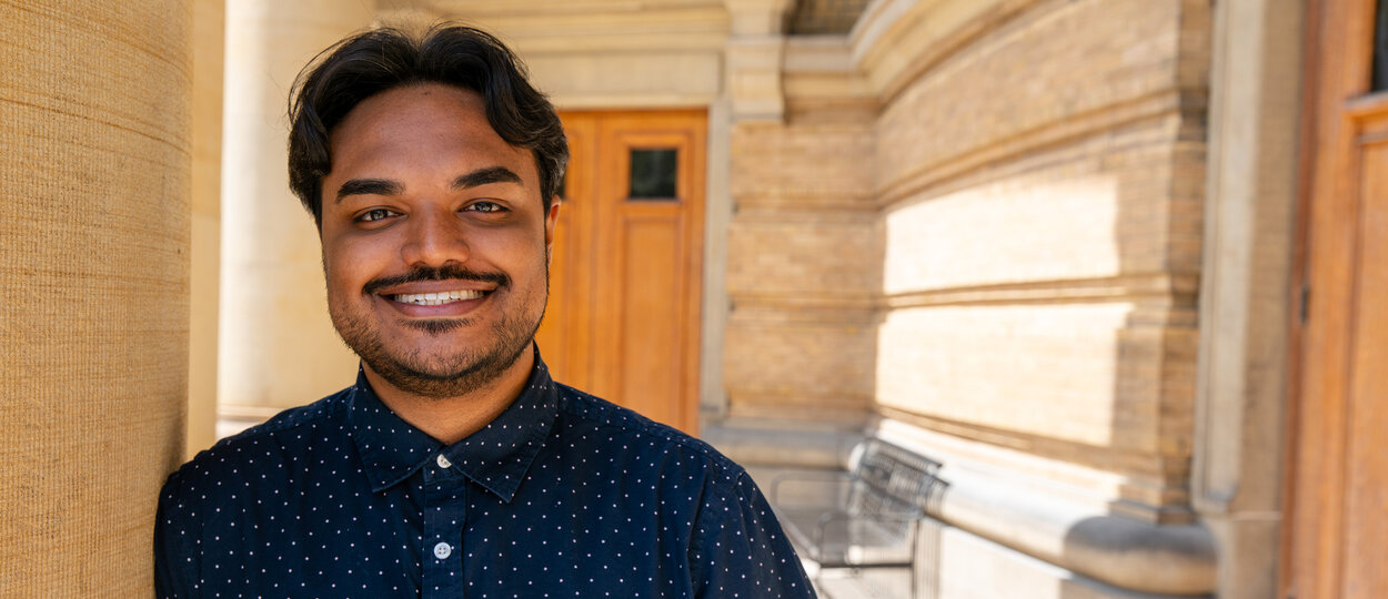 2T4 Valedictorian Al-Amin Ahamed leaning against pillar at convocation hall