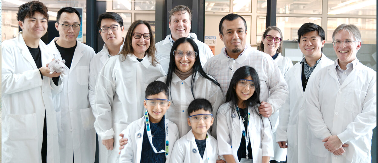 Group of people in labcoats posing out front of lab