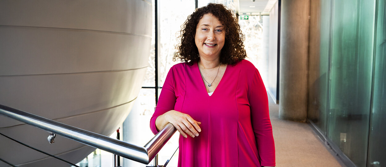 Portrait of Dean Lisa Dolovich standing in Leslie Dan Faculty of Pharmacy building next to second floor lecture pod.