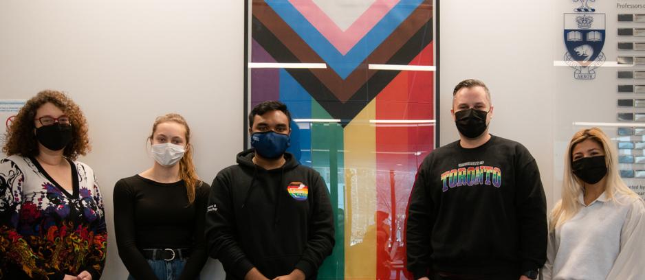 Members of PharmaPride student group alongside Dean Lisa Dolovich and Jaris Swidrovich in front of inclusion pride flag 