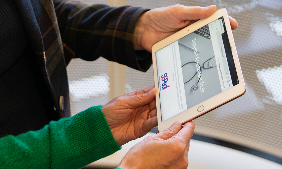Dupuis and Sung holding a digital tablet displaying the Symptom Screening in Pediatrics Tool (SSPedi, pronounced “speedy”)