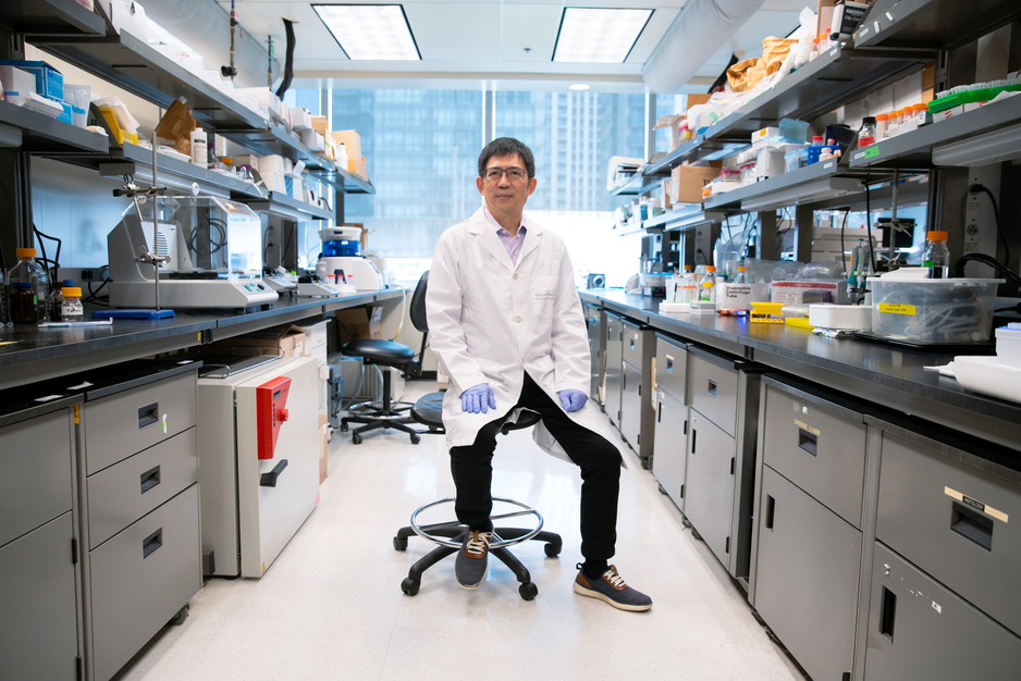Professor Gang Zheng sitting in his lab surrounded by lab benches