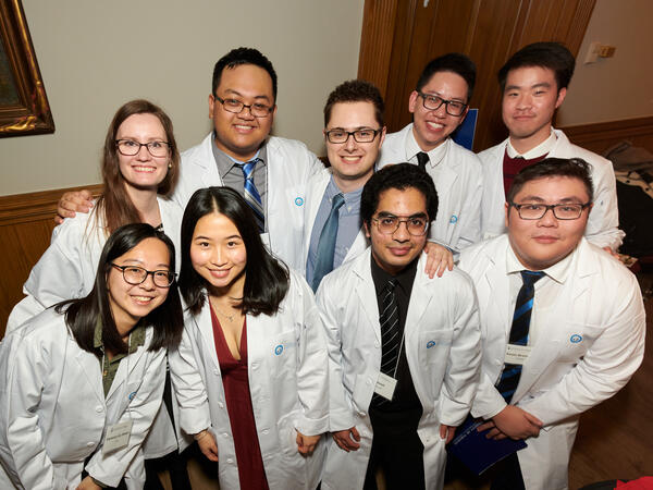 Students posing for photograph in white coats