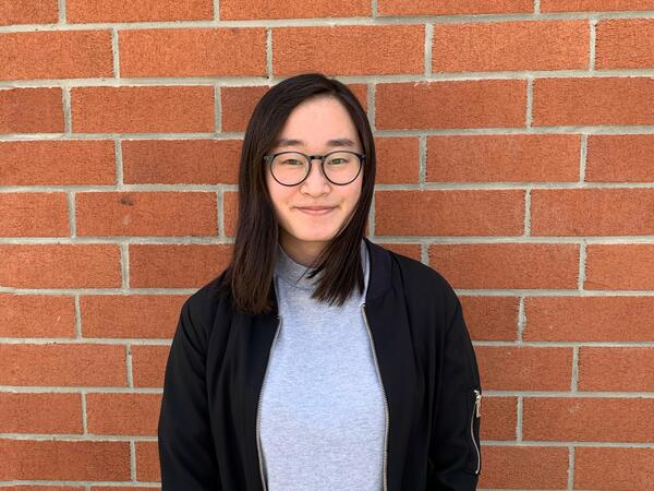 Portrait photo of U of T student Jenny Cheung against brick wall