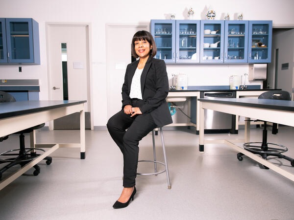 Lachmi Singh sitting in front of blue pharmacy cabinets