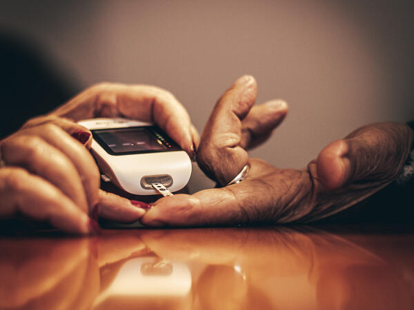 Elderly patient hands testing blood sugar with glucose monitor