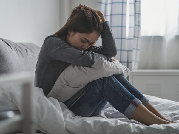 Young women sitting in bed in pain Young women sitting in bed in pain