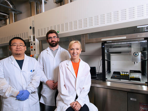 Phd Trainee Zeqing Bao, Allen Lab Director Pauric Bannigan and Professor Christine Allen posing in the Allen lab next to self-driving lab prototype