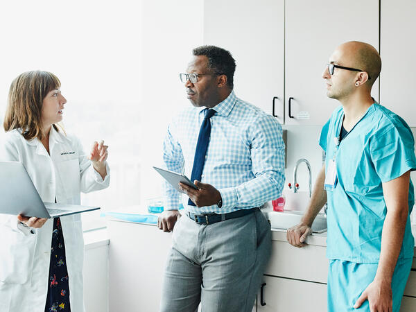 Female doctor leading medical team discussion in hospital exam room