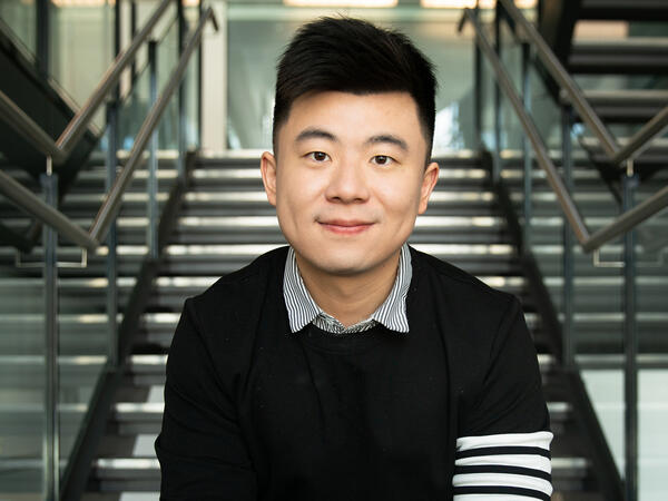 Professor Bowen Li sitting on steps at the Leslie Dan Faculty of Pharmacy