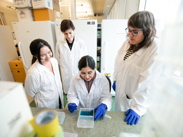 Assistant Professor Rachel Harding with lab members in lab coats talking