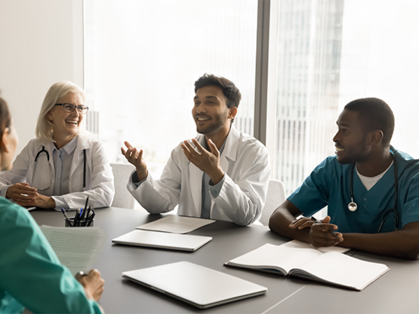 Four health care professionals chatting around a table Four health care professionals chatting around a table