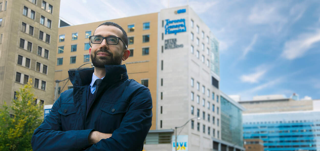 Photo of PharmD for Pharmacists alumni Al-Harith Mohammad infront of Toronto Hospital with blue sky