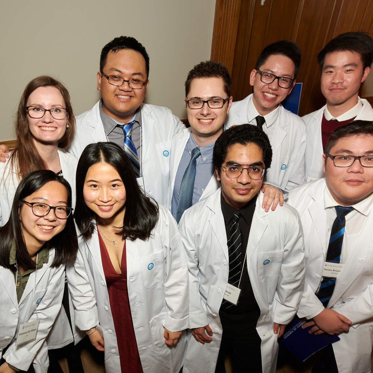 Students posing for photograph in white coats